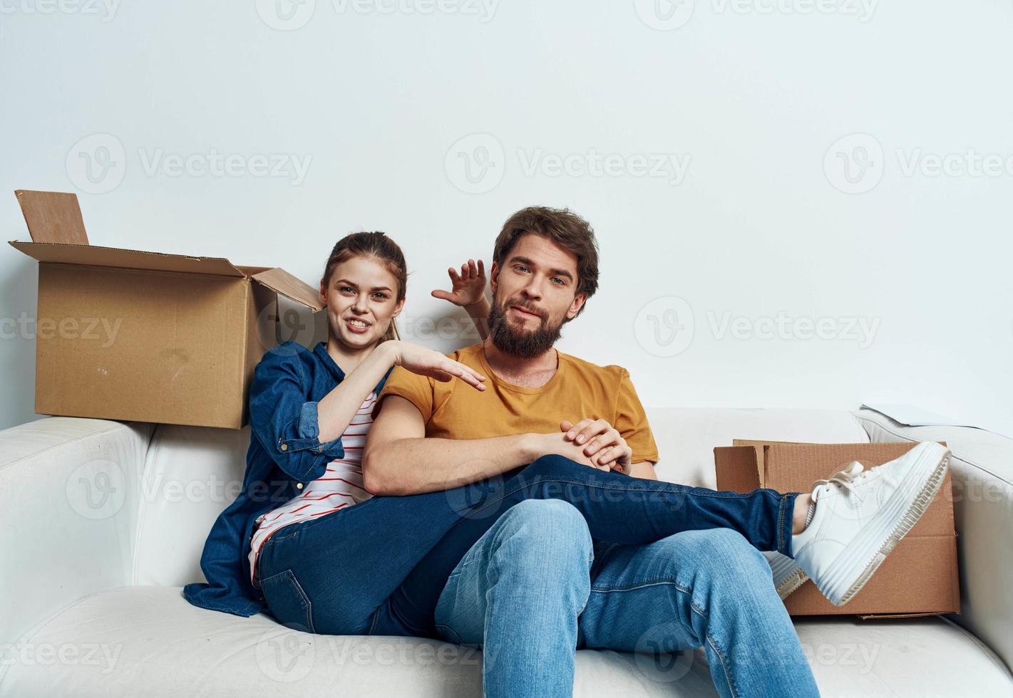 young couple sitting on white couch boxes moving lifestyle photo