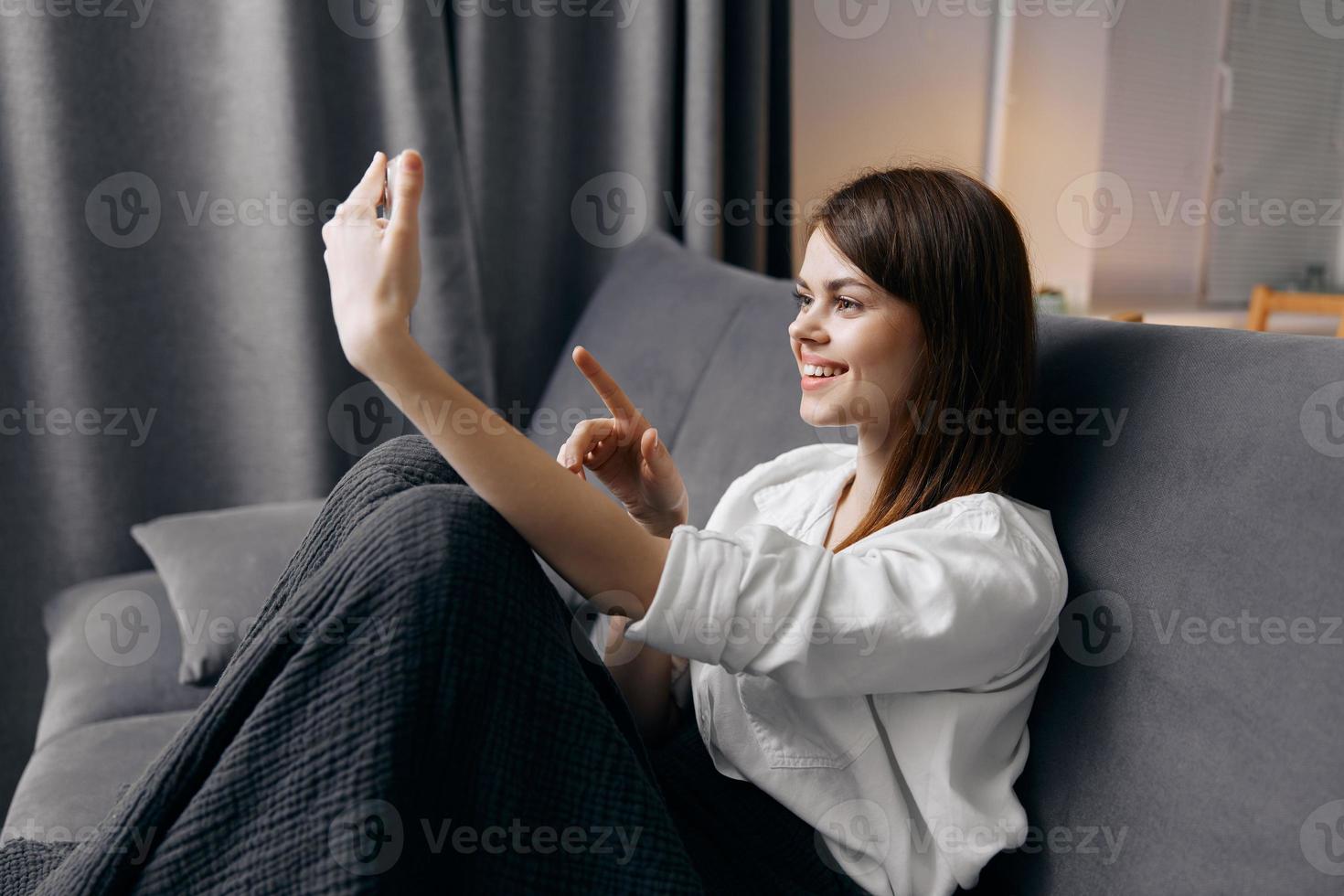 happy woman sitting on gray sofa indoors comfortable room photo