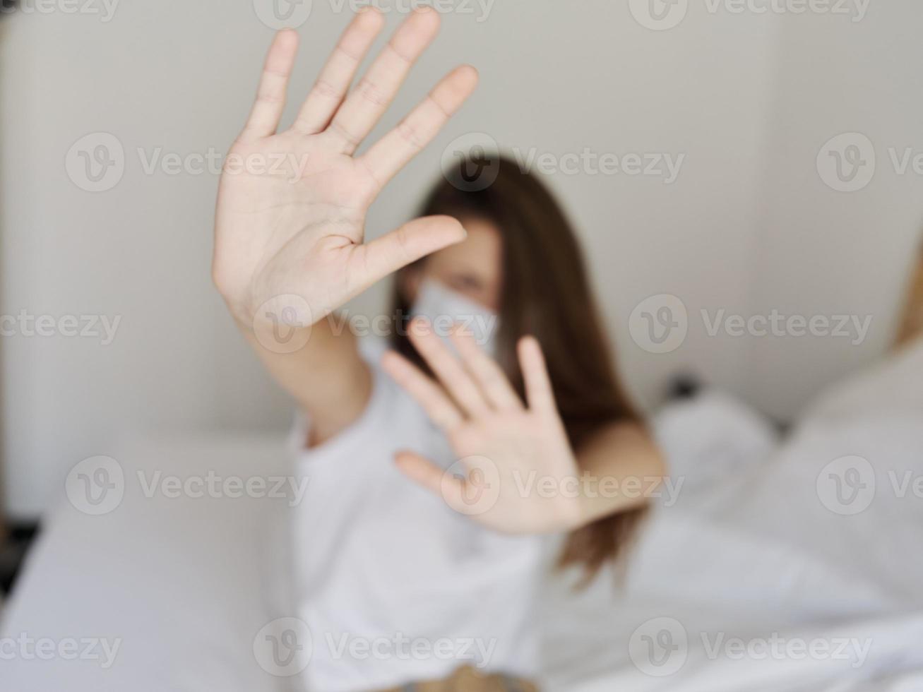 woman gesturing with hands sitting on bed medical mask isolated room quarantine model photo