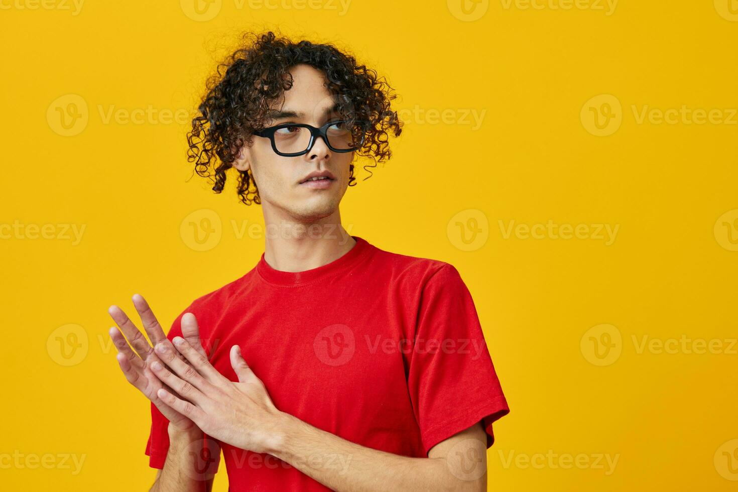 Lovely myopic young student man in red t-shirt funny eyewear looks aside posing isolated on over yellow studio background. The best offer with free place for advertising. Education College concept photo