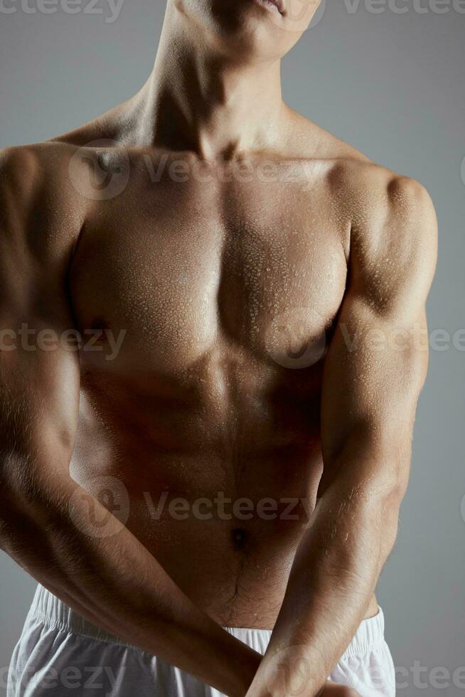 athlete with muscular body in white shorts joined hands on gray background cropped view photo
