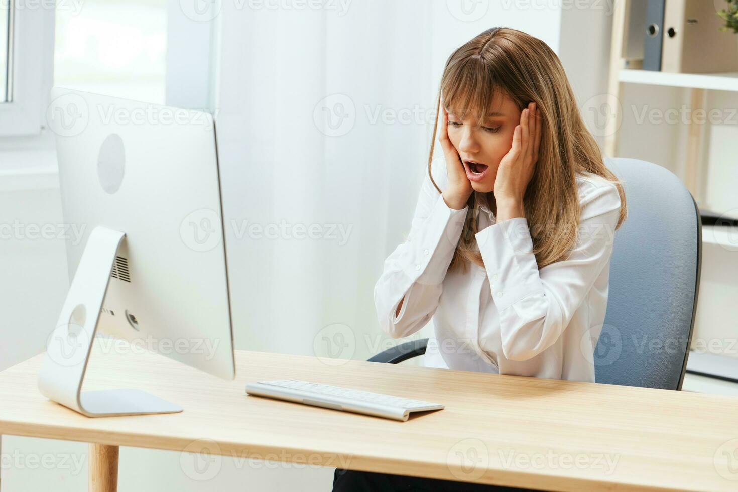 Shocked upset adorable blonde businesswoman worker touch chin both hands thinking of problem solution in light modern office. Employee work on computer online pondering or making decision. Copy space photo