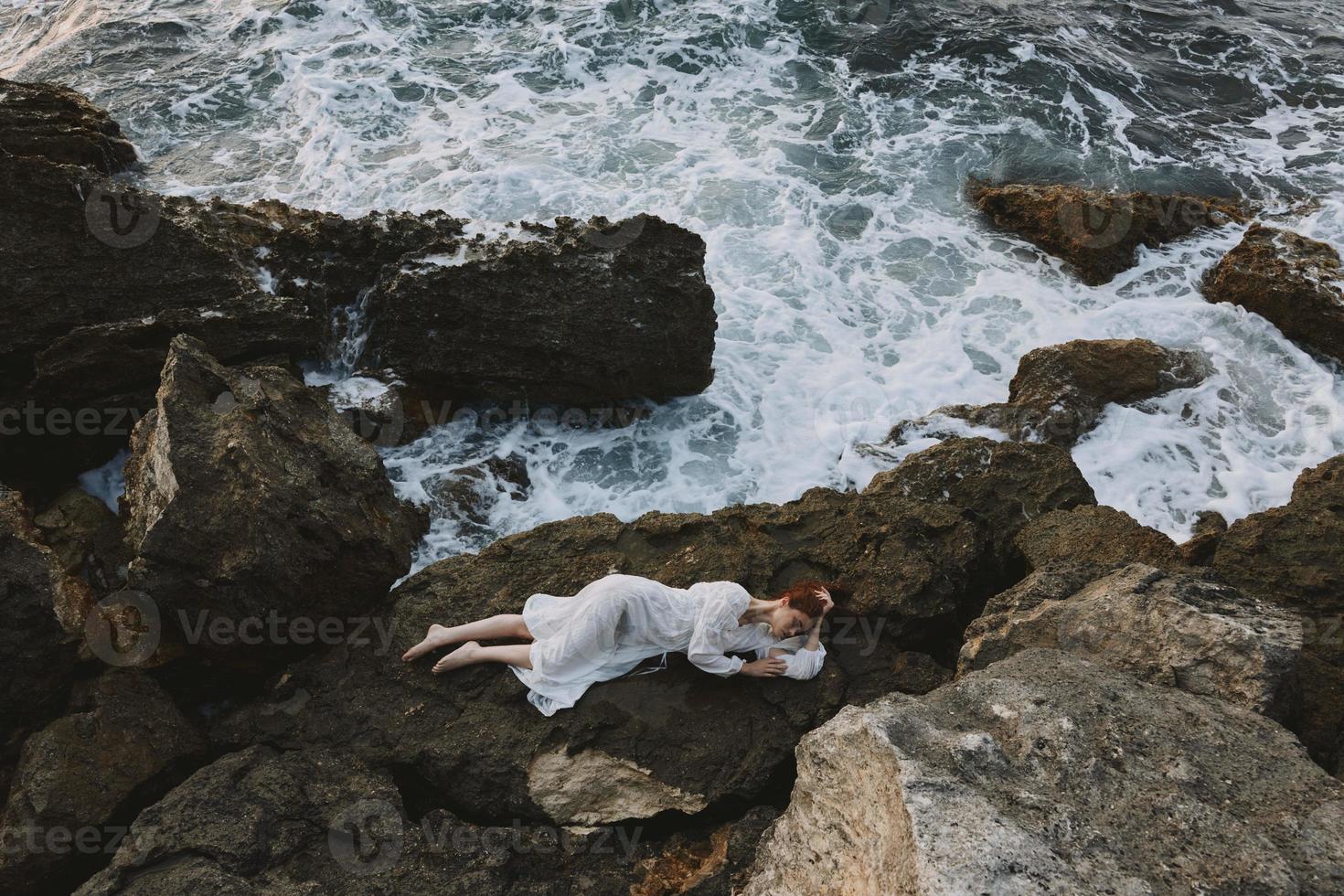 Beautiful bride lying on rocky coast with cracks on rocky surface unaltered photo