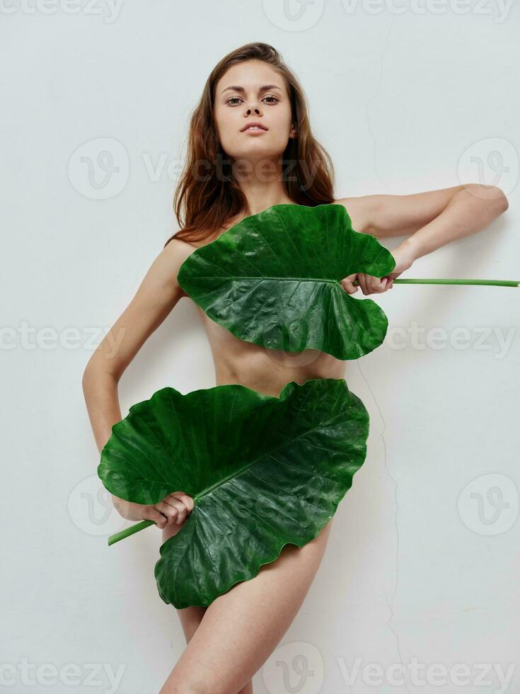 red-haired woman green leaves nude body charm light background photo