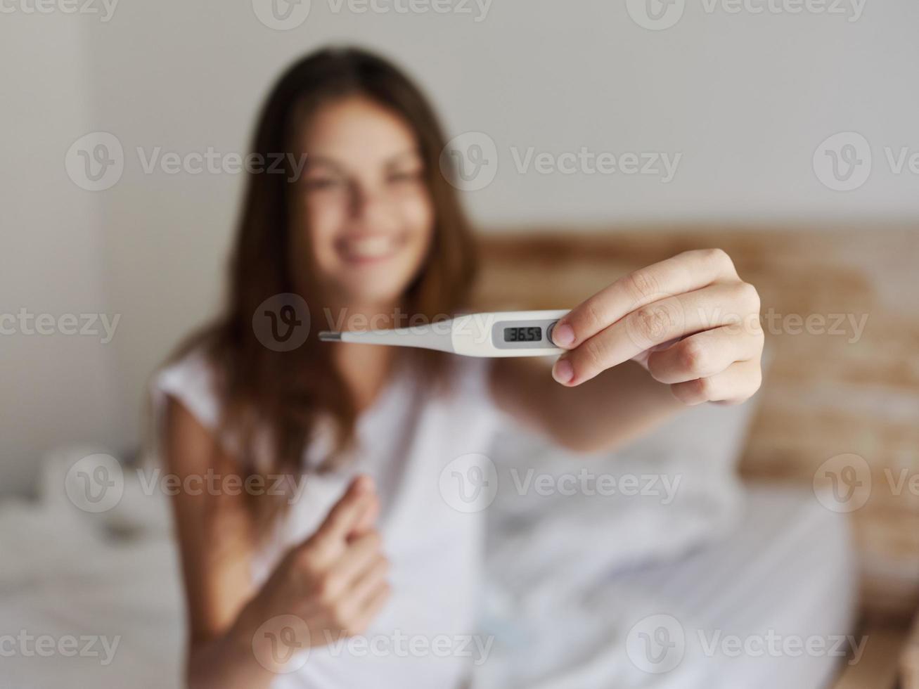 woman shows a positive temperature result on the thermometer photo