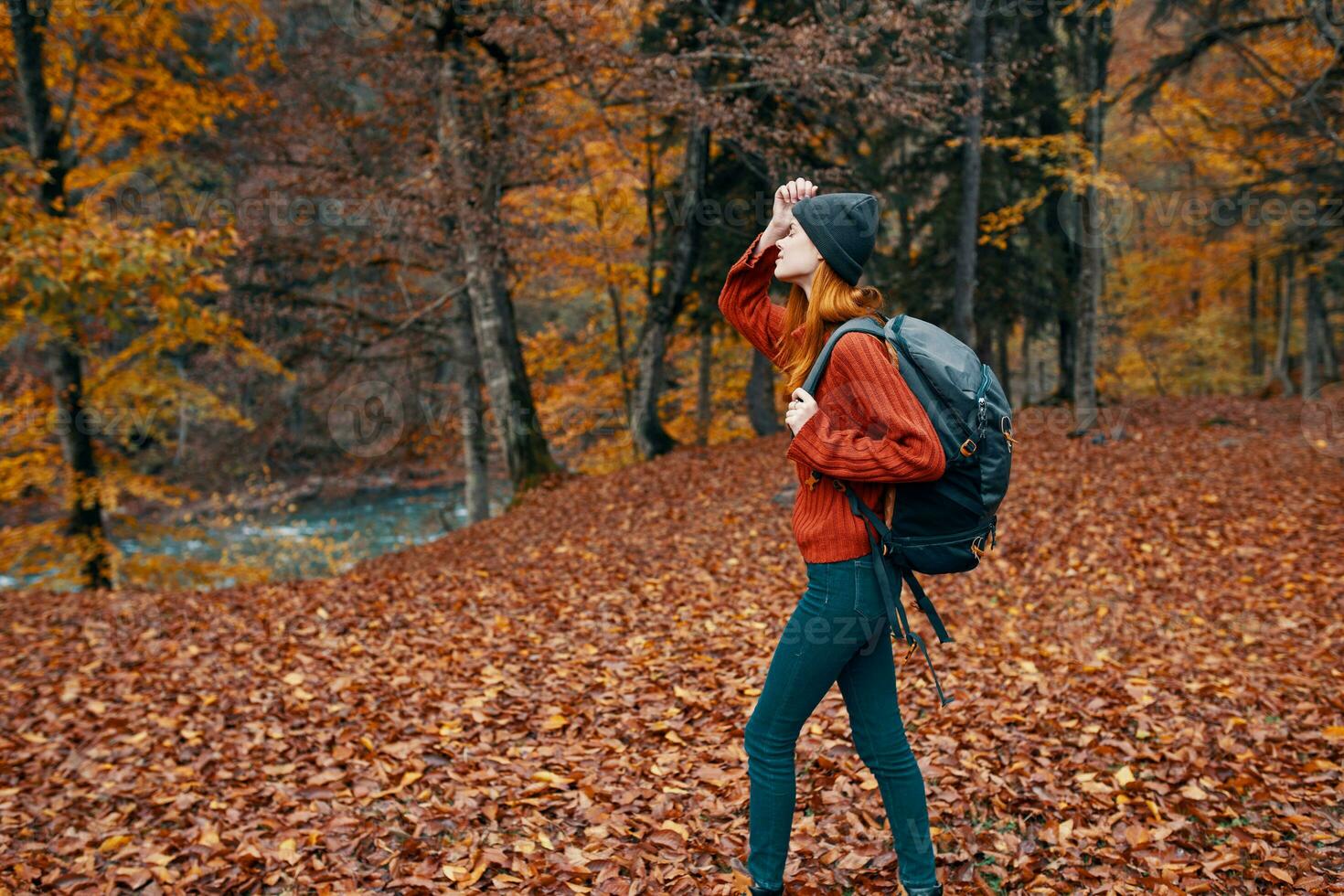 contento viaje mujer con mochila camina mediante el otoño parque en naturaleza cerca el río paisaje alto arboles suéter foto