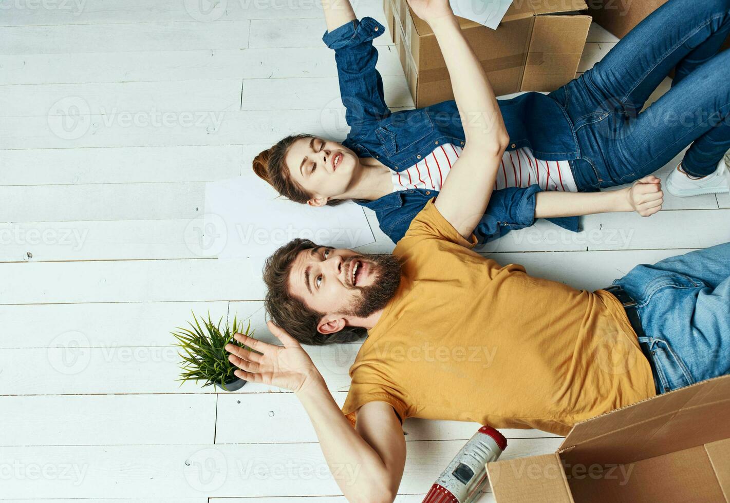 Man and woman with boxes on the floor a flower in a pot moving to repair work photo