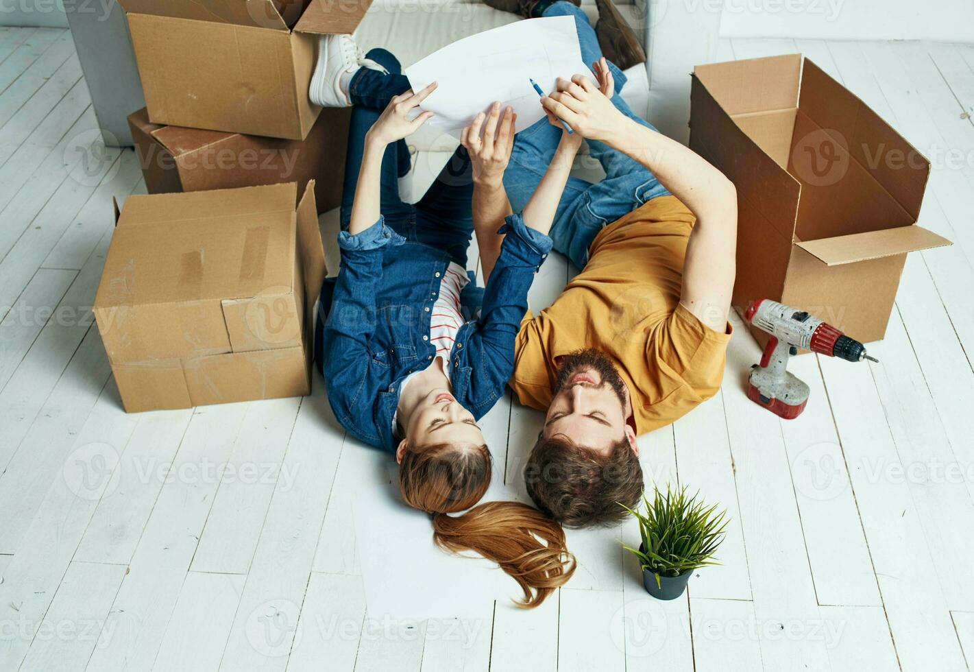 Men and women lie on the floor indoors with boxes of documents of flowers in a pot moving photo