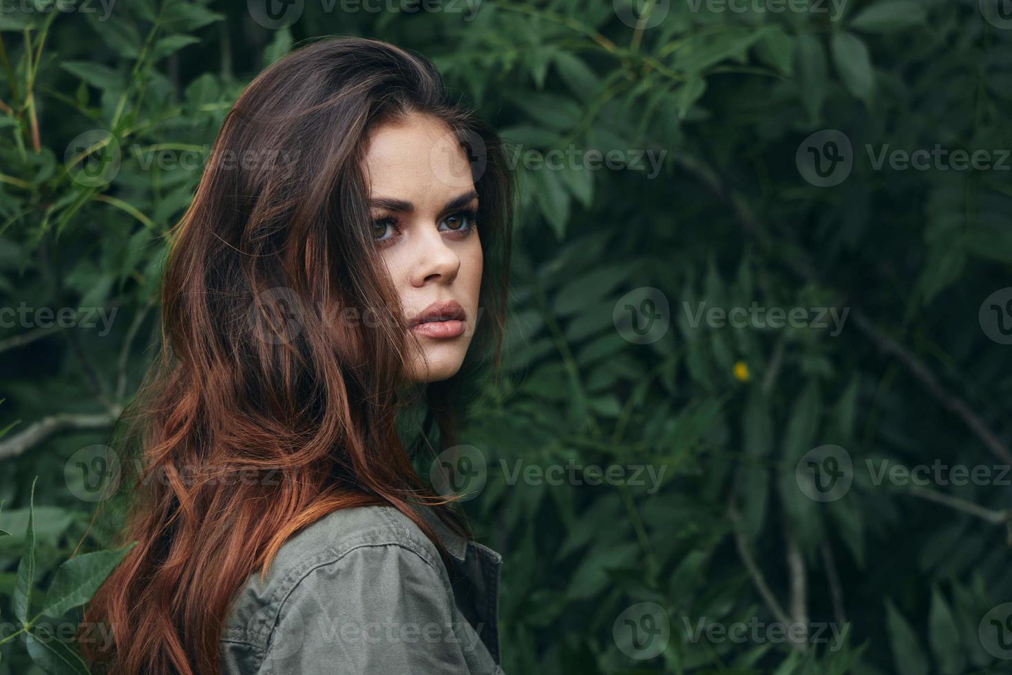 Portrait of a woman Green shirt red hair side view green leaves photo