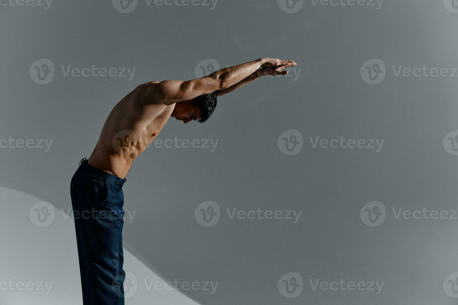 bodybuilder Fitness man with a pumped-up torso and with raised arms leaned forward side view photo