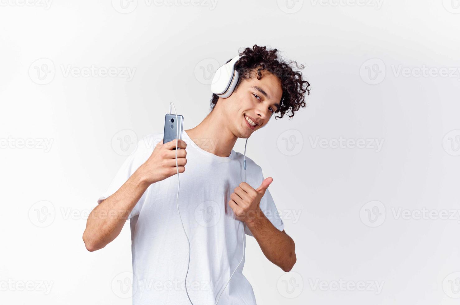 curly-haired guy in white t-shirt with headphones music technology entertainment photo