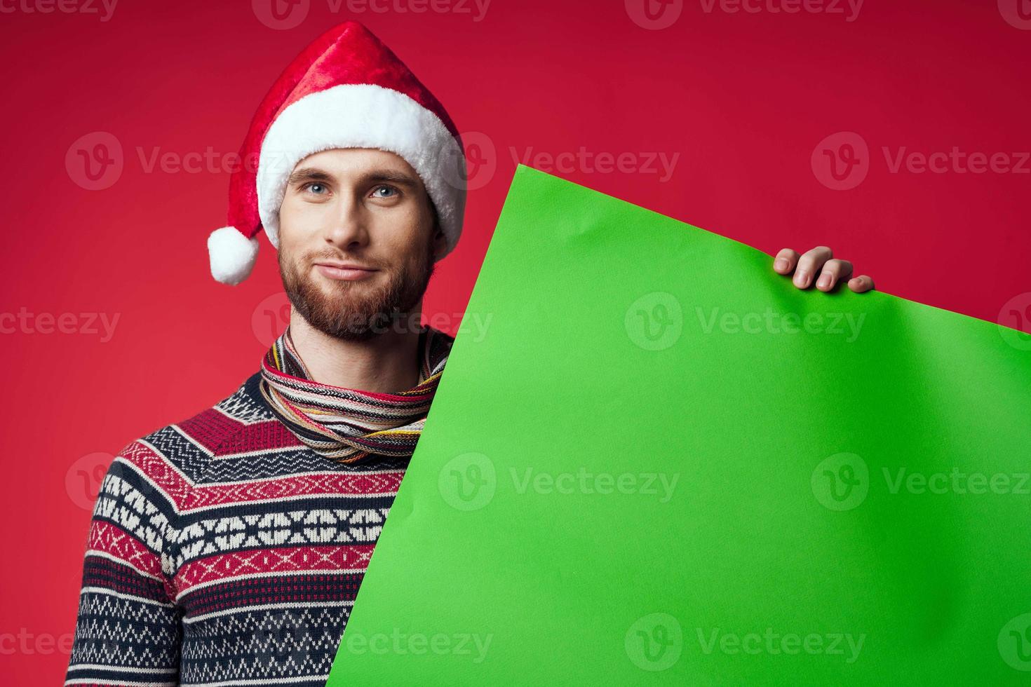 emotional man in a christmas hat with green mockup red background photo