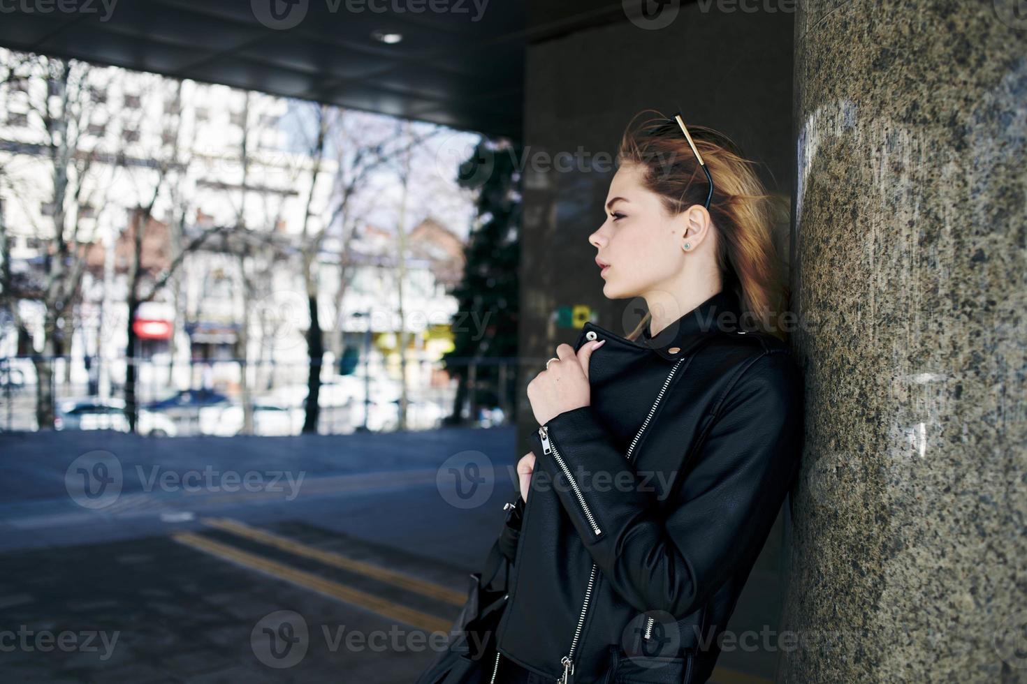 woman in leather jacket on the street in the city and edition sunglasses in the background photo