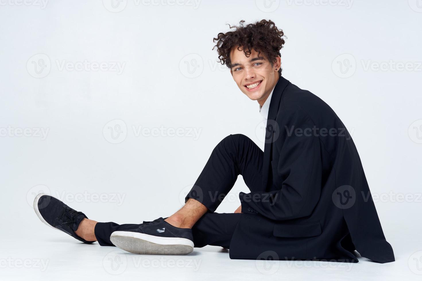 business man curly hair fun suit sitting on the floor light background photo