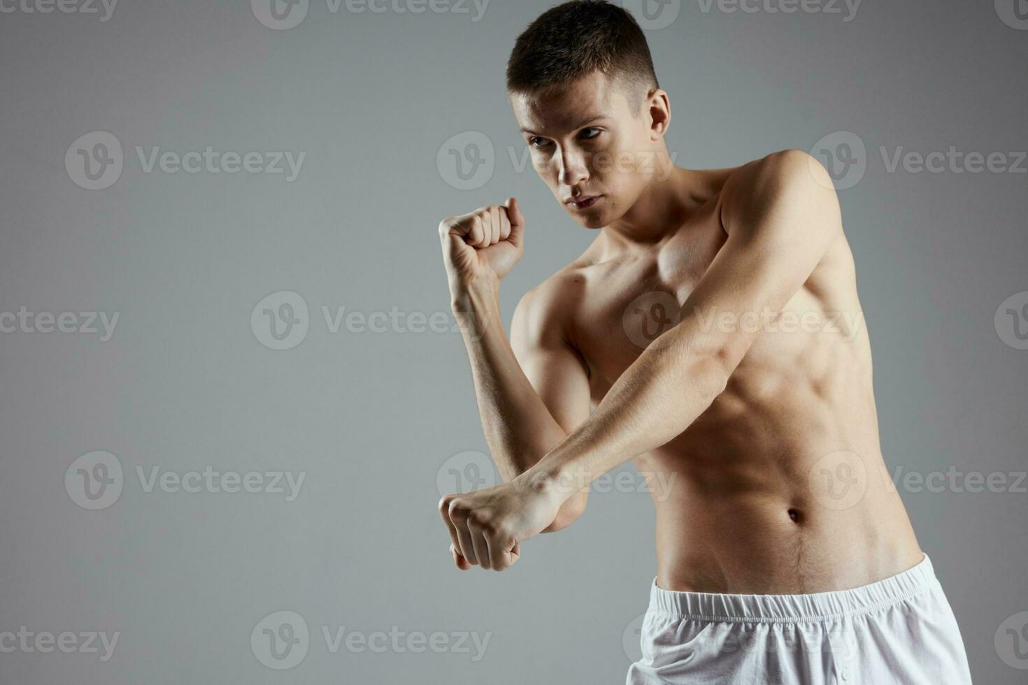 boxer with pumped up arm muscles on a gray background and abs cubes on his stomach photo