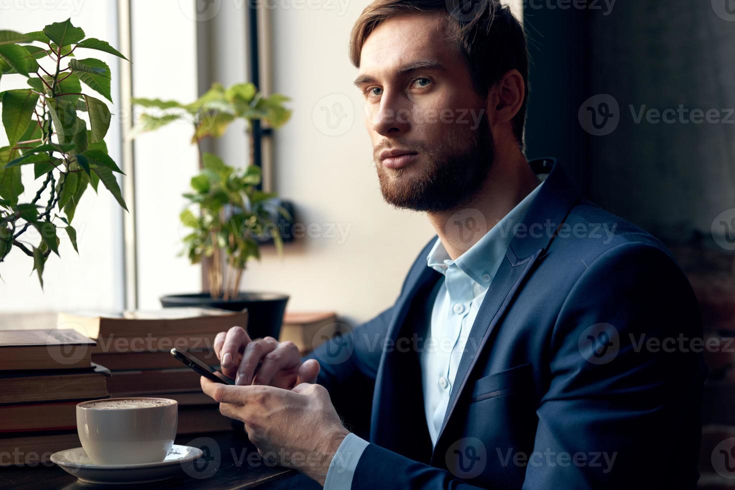 hombre con un teléfono en su manos sentado en un café ocio trabajo estilo de vida empresario foto