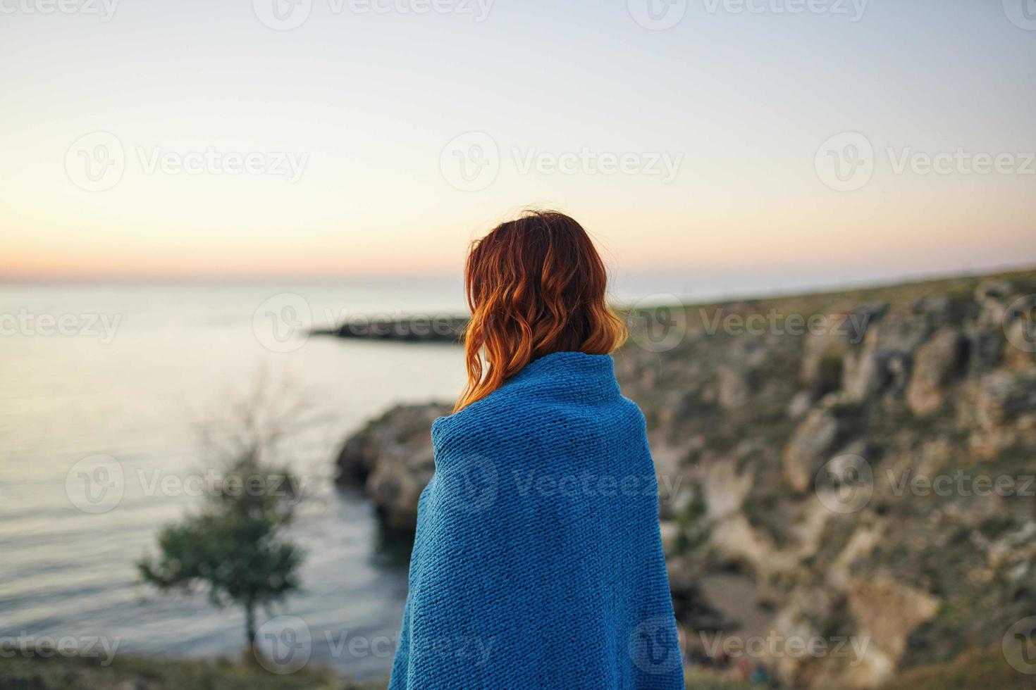 mujer en naturaleza ocultación con un cobija en el Mañana admira el paisaje foto