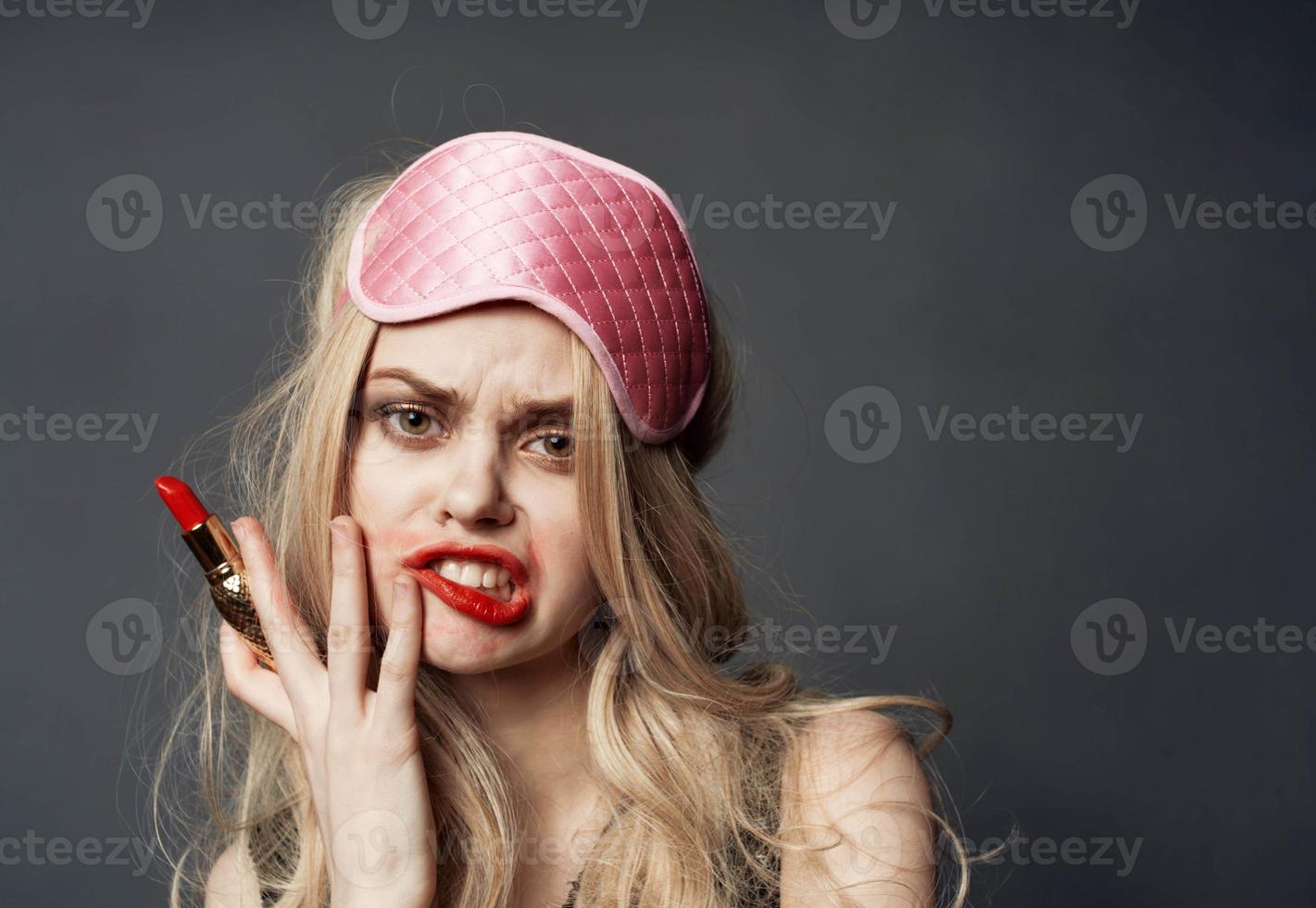 Drunk woman with lipstick in hand and pink mask on her face photo