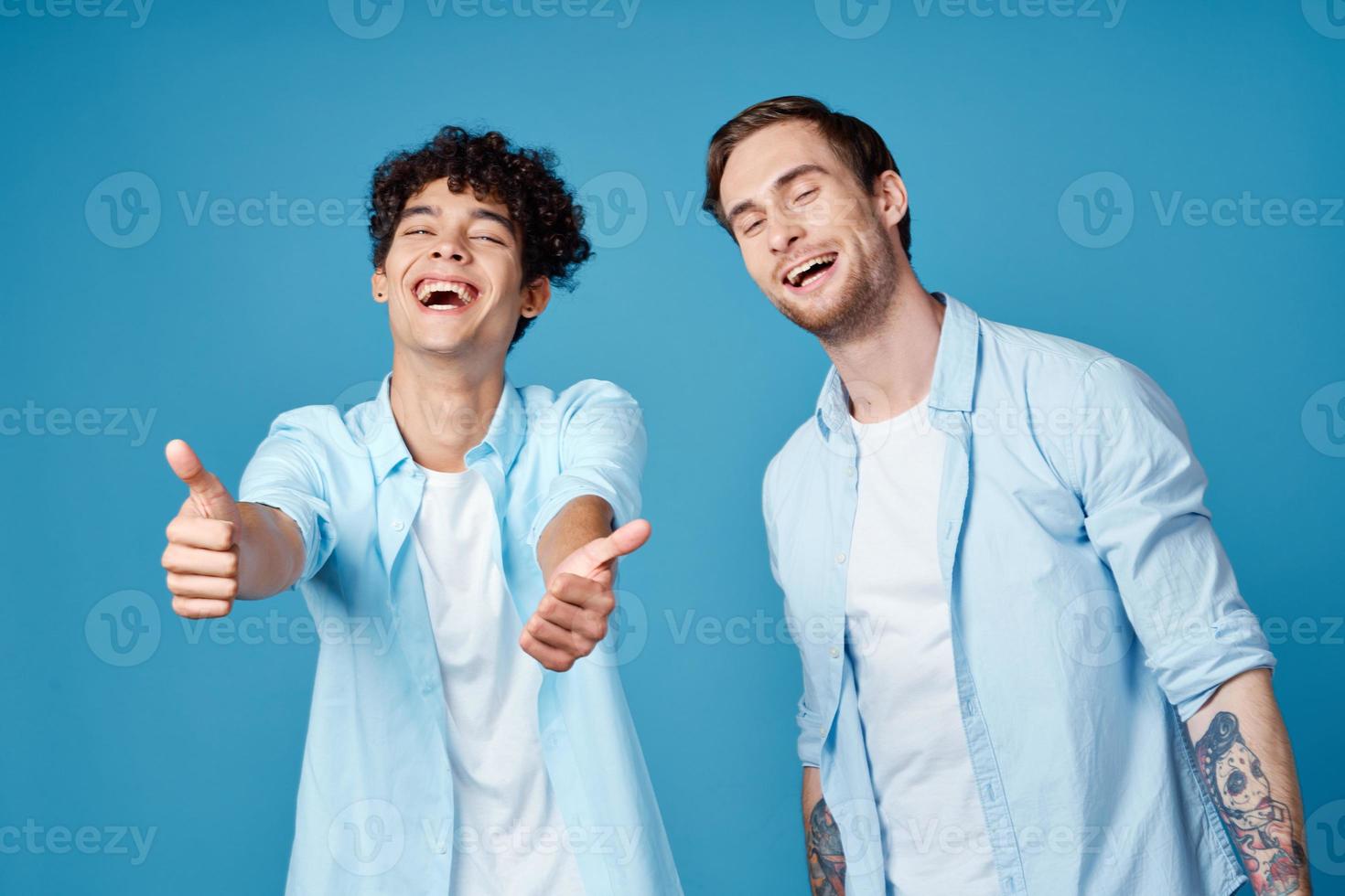 young guys in the same shirts and t-shirts are gesturing with their hands on a blue background friends photo
