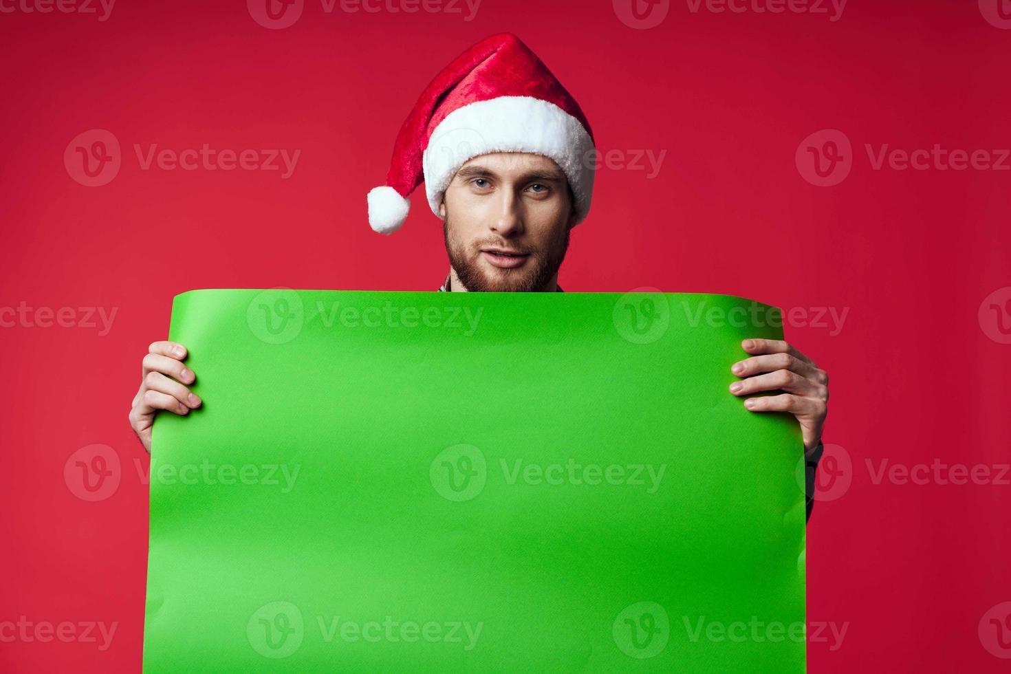 emotional man in a santa hat holding a banner holiday red background photo