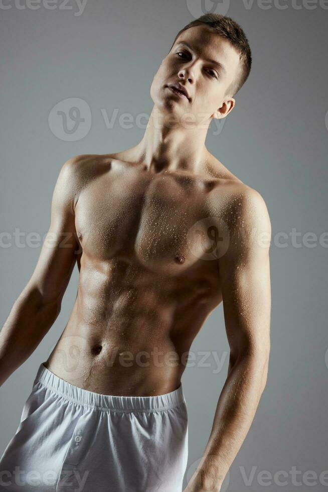 bodybuilder with a pumped up torso in white shorts on a gray background cropped view close-up photo