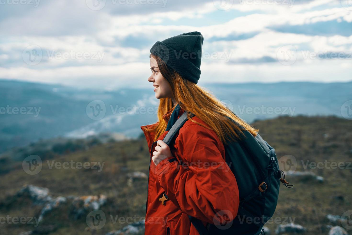 mujer viajes en el montañas paisaje mochila rojo chaqueta y sombrero modelo foto