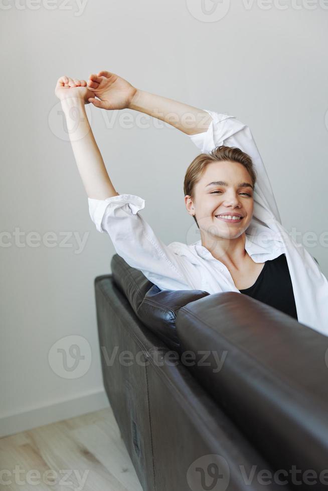 Women lying at home on the couch portrait with a short haircut in a white shirt, smile, depression in teenagers, home holiday photo