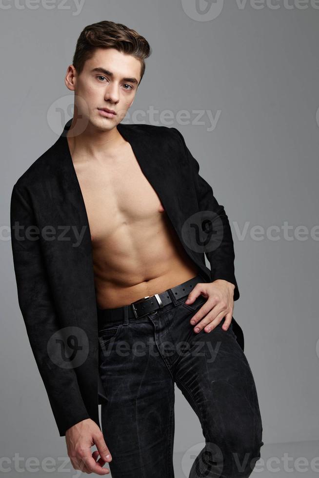 The man in the jacket holds his hand on his belt and leans to the side photo