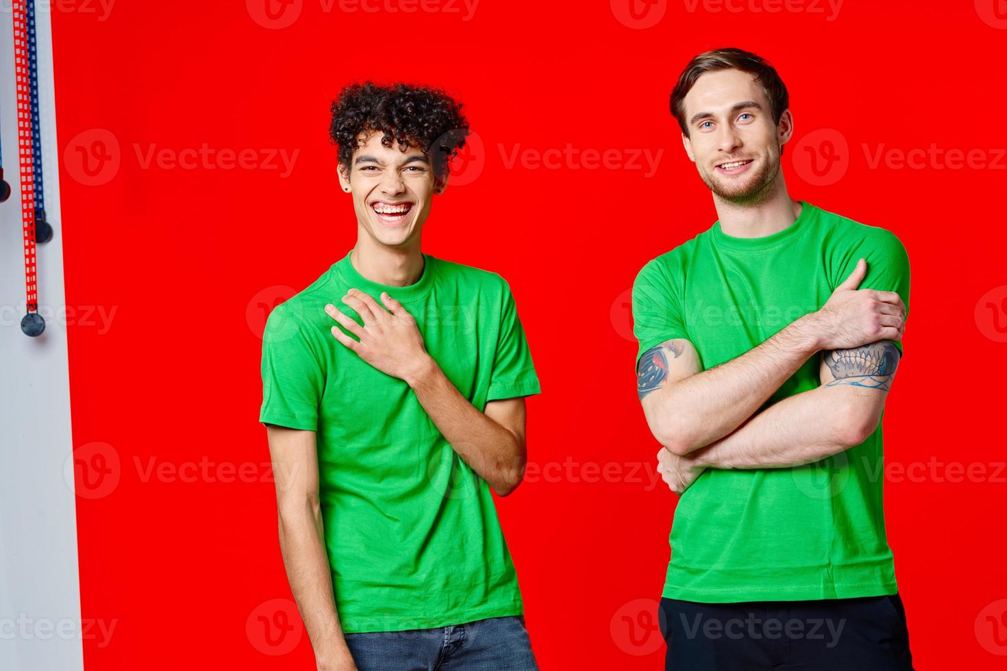 two men in green t-shirts are standing next to friendship red background photo