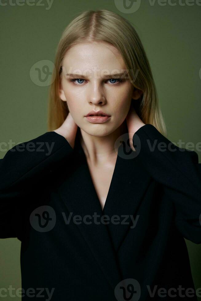 The head portrait of a charming beautiful girl in a black jacket poses on a green background in the studio. Cool banner for brands. Cool offer for design photo