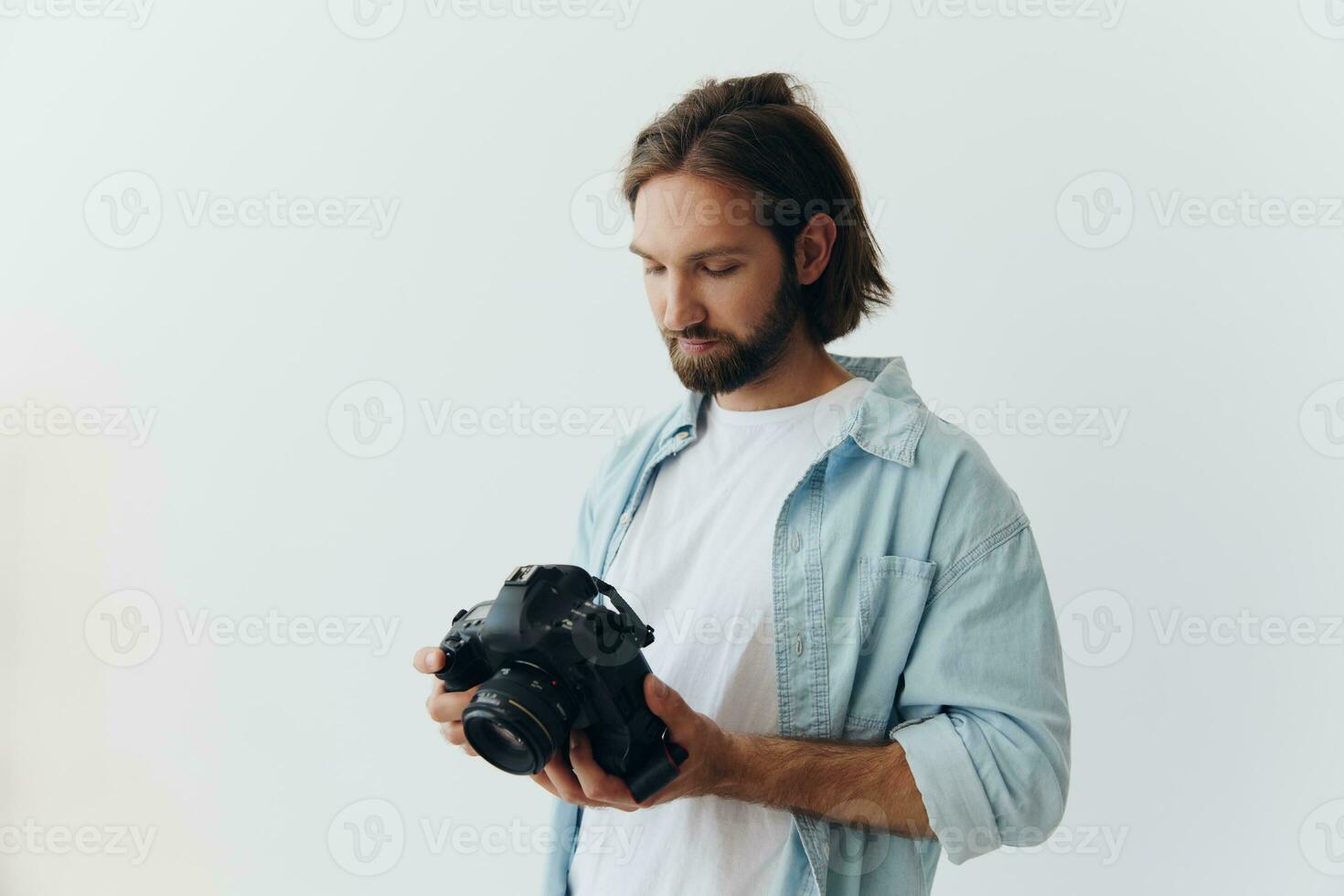 Man hipster photographer in a studio on a white background looking at the camera screen and setting it up for a photo shoot