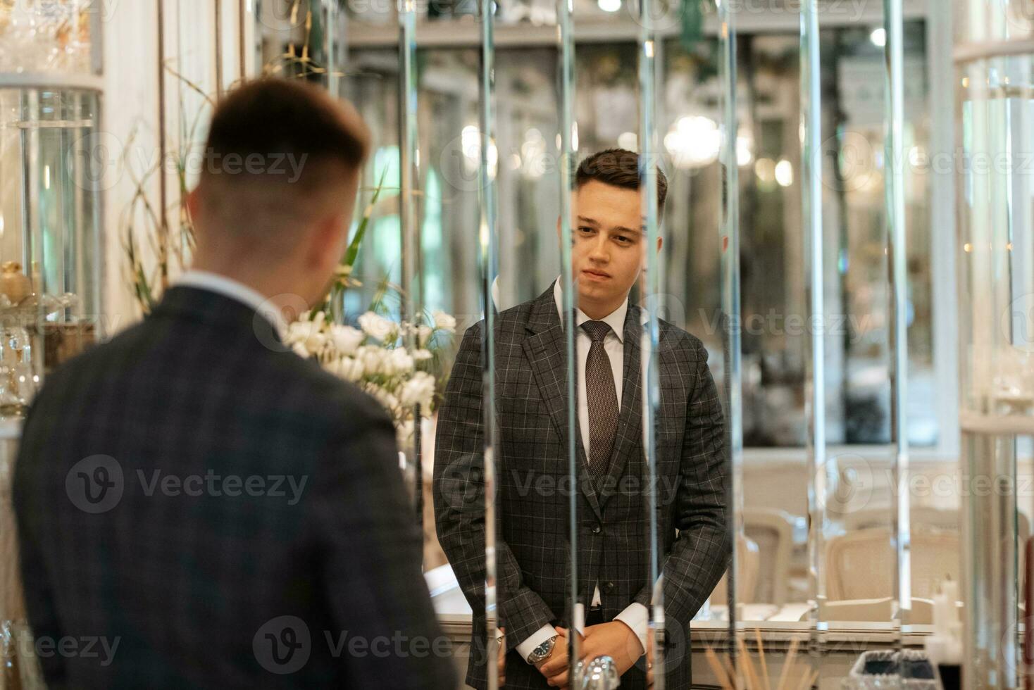 portrait of a groom in a gray plaid suit with a tie in a light bar photo