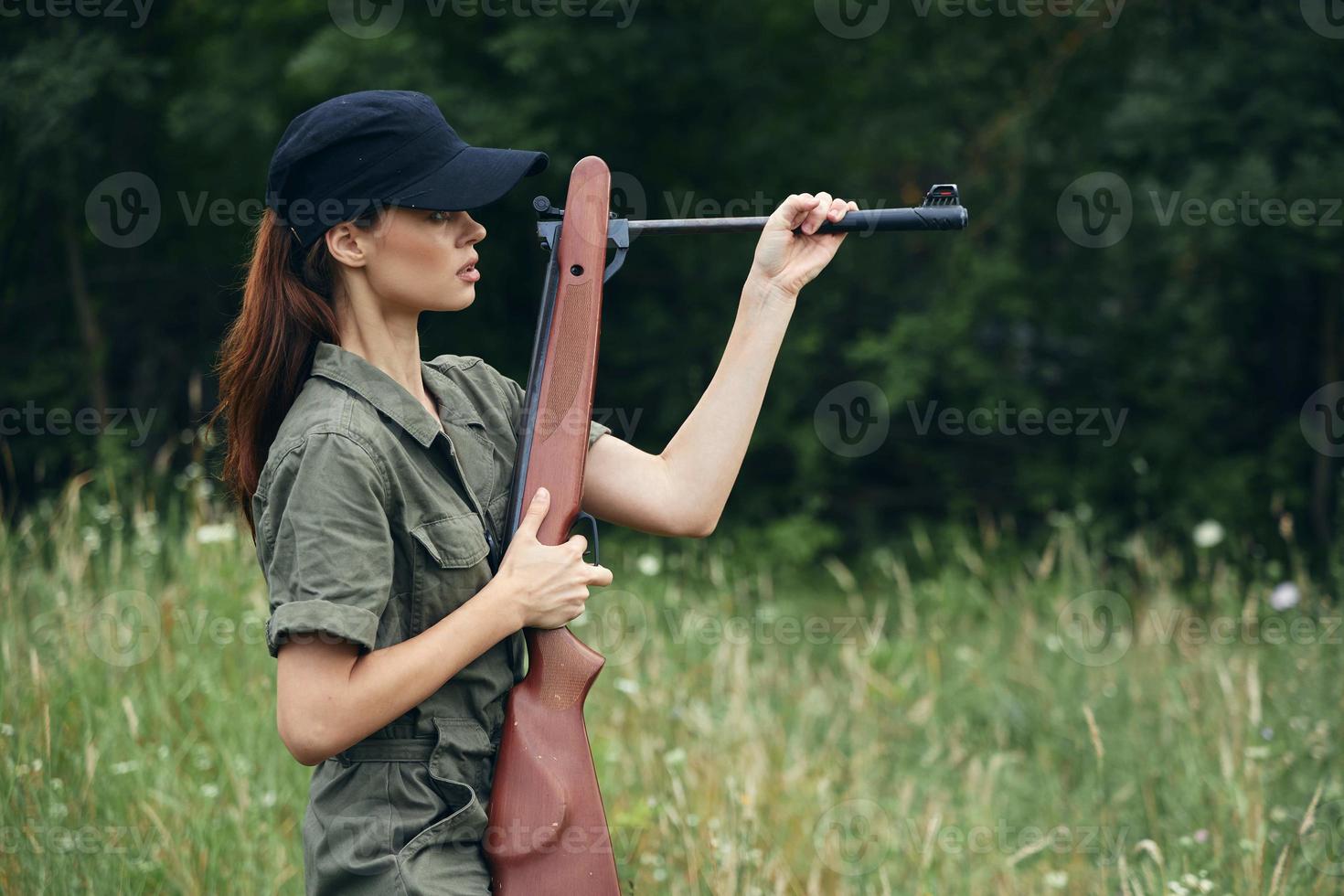 Military woman gun in hand reloading green grass black cap photo