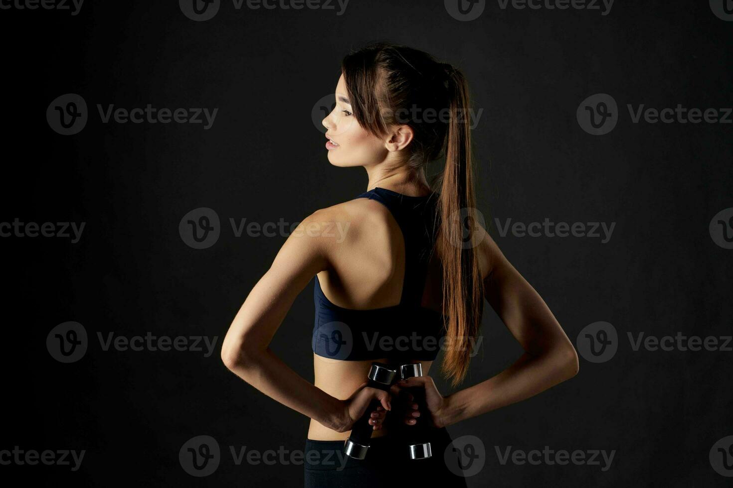 woman with dumbbells in hands dark background workout inflated muscles photo