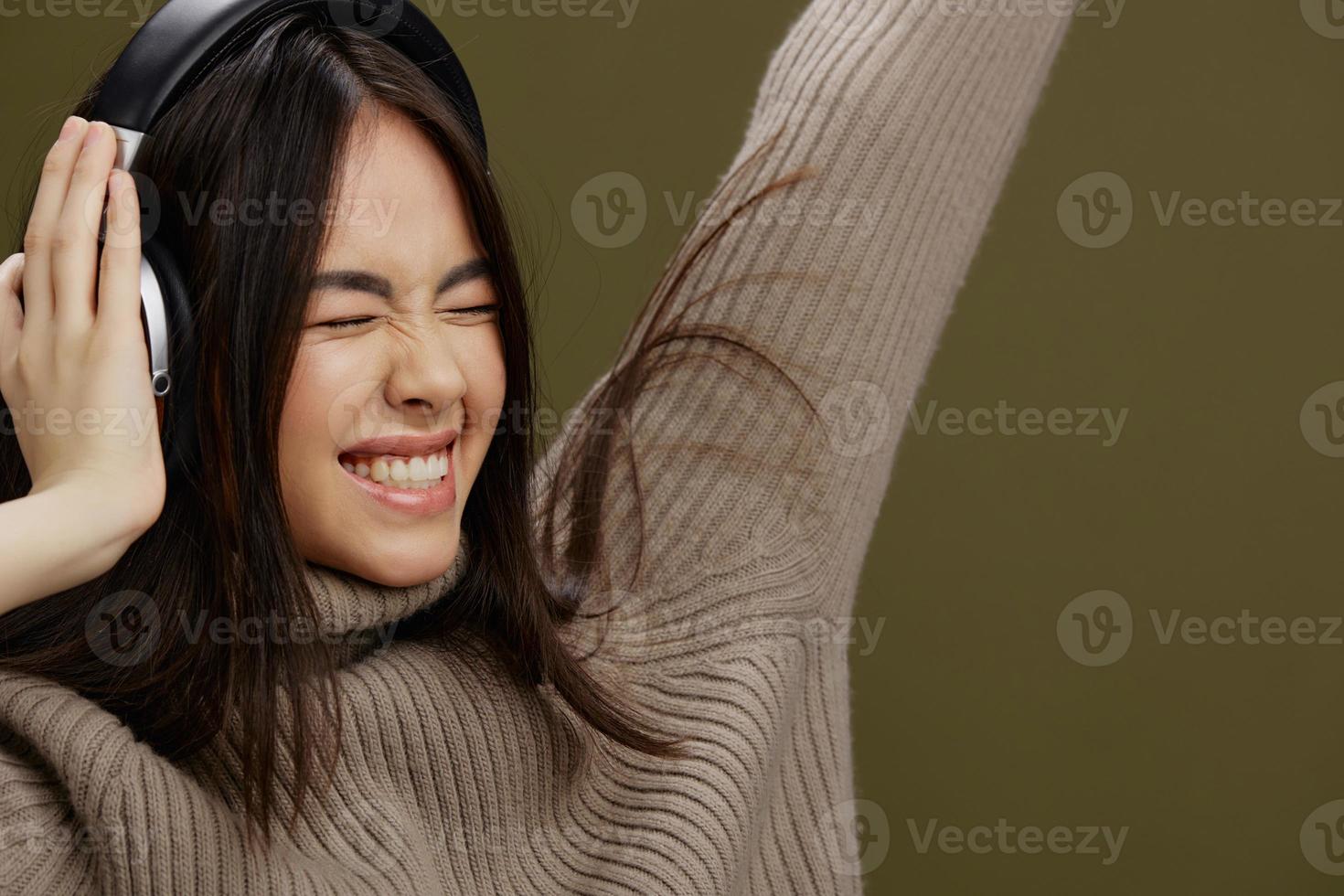 woman in a sweater listening to music with headphones fun Green background photo