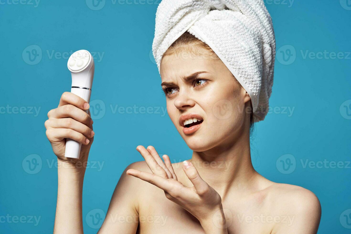 cheerful woman with a towel on the head of the massager in her hands skin care photo