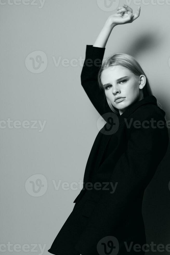 Fashion model girl posing with her hands up in the studio in black and white style in a classic jacket photo