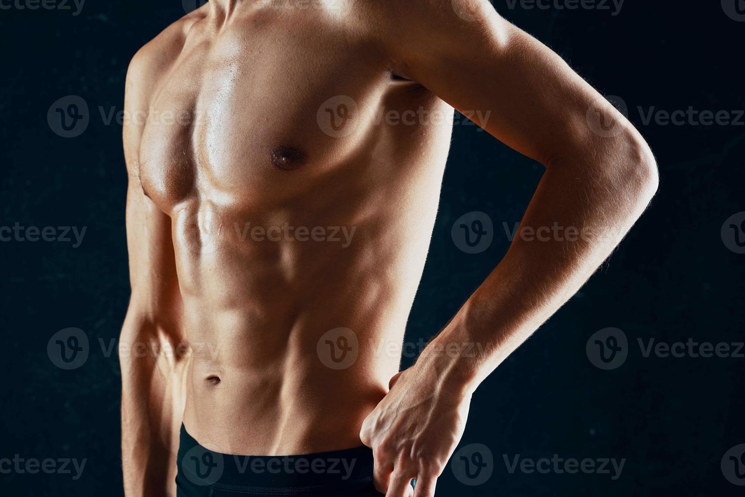 sporty man with a pumped-up muscular body in a towel dark background photo
