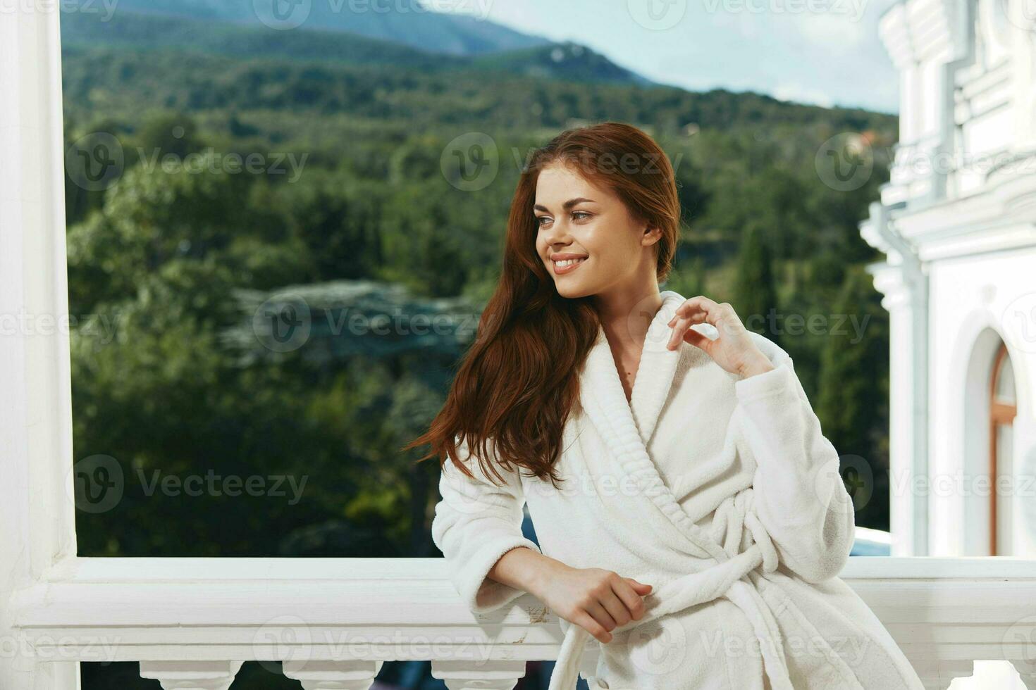 beautiful woman in a white robe on the balcony bit on green nature hotel room photo
