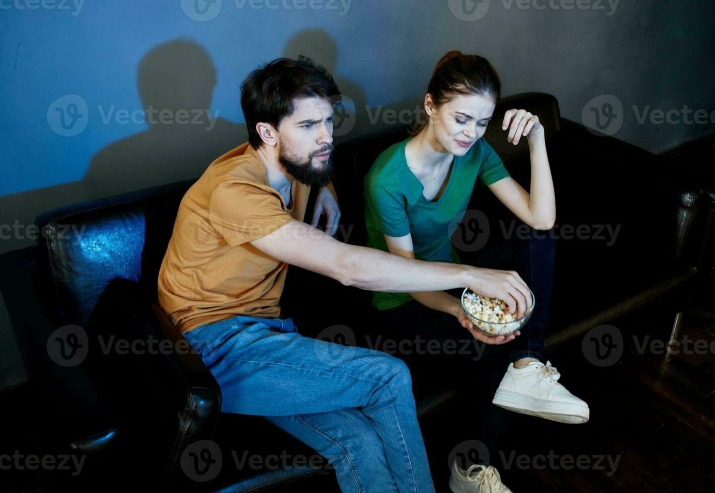 A man and a woman are watching a movie in the cinema on the sofa indoors photo