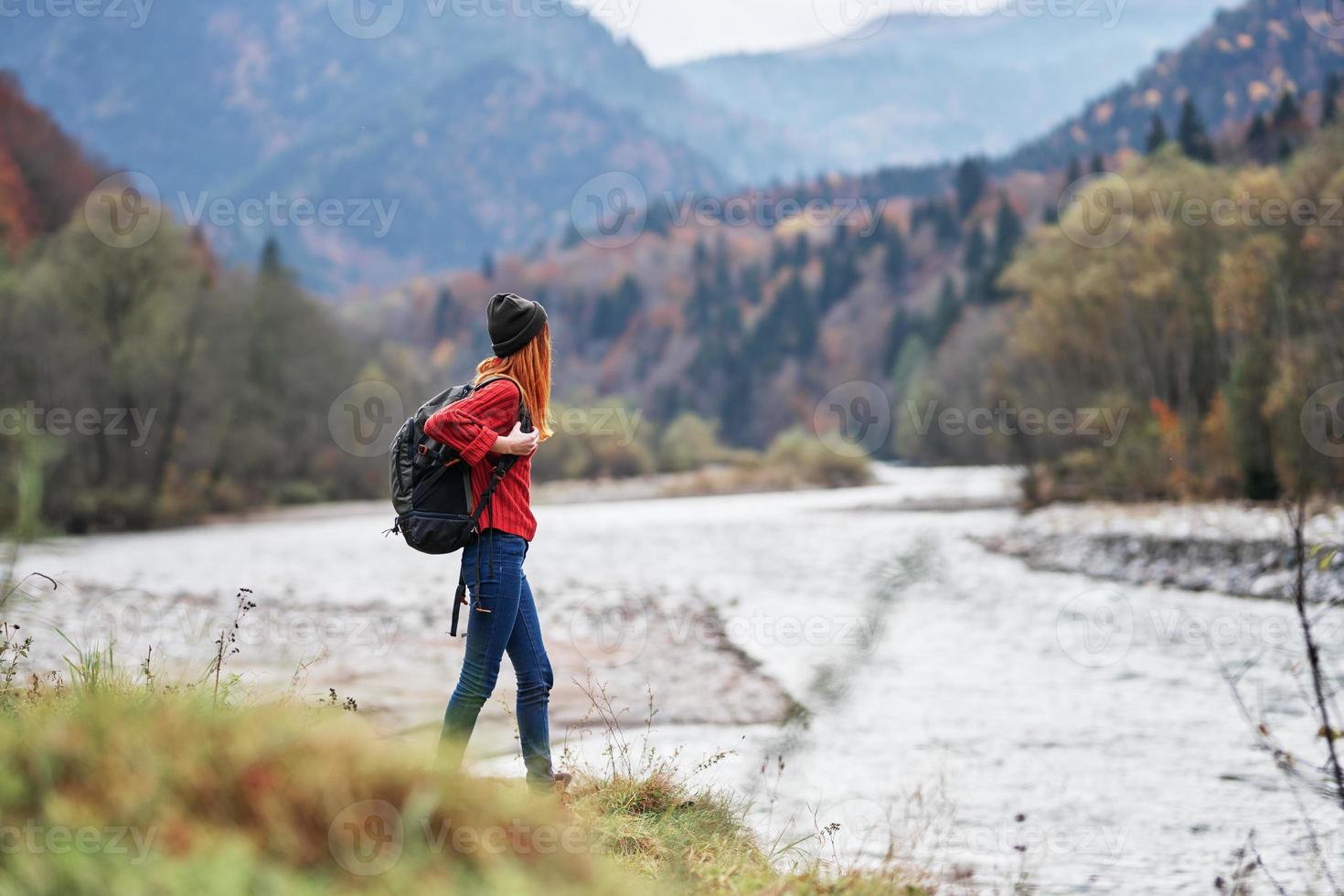 woman in a red sweater with a backpack in the mountains on nature near the river pond lake photo