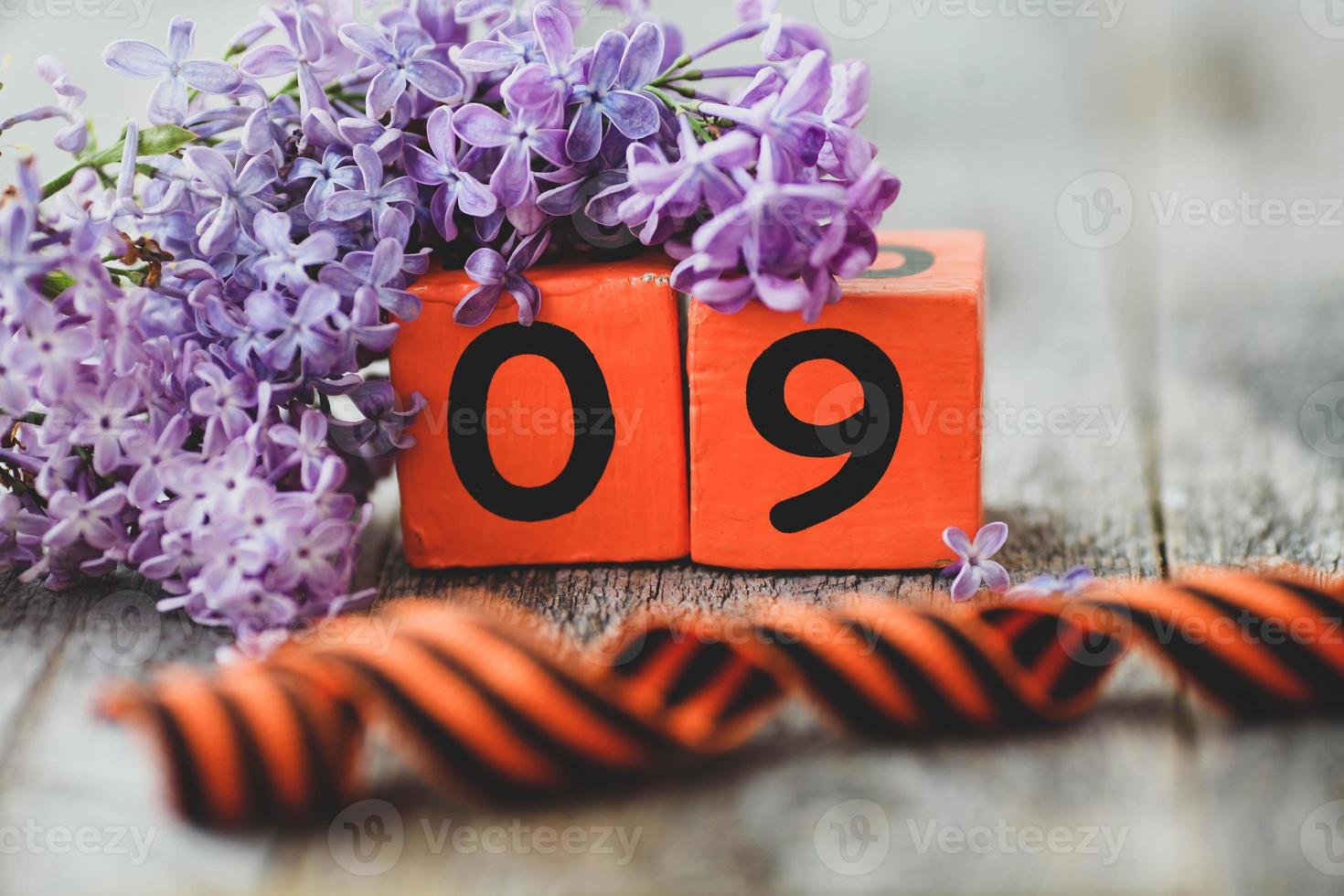 de madera calendario con ruso texto mayo 9, Jorge cinta y un ramo de flores de lilas en un de madera antecedentes. victoria día. foto