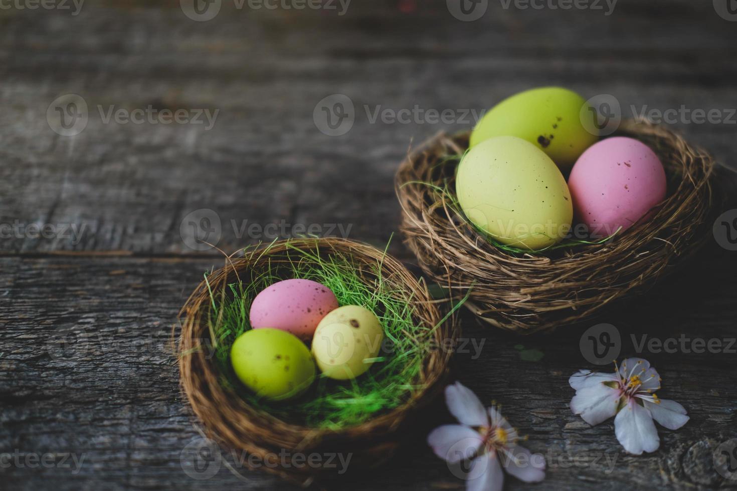 Easter quail painted eggs  in a nest and spring flowers on a  wooden background.   An Easter card with a copy of the place for the text.Top view. photo
