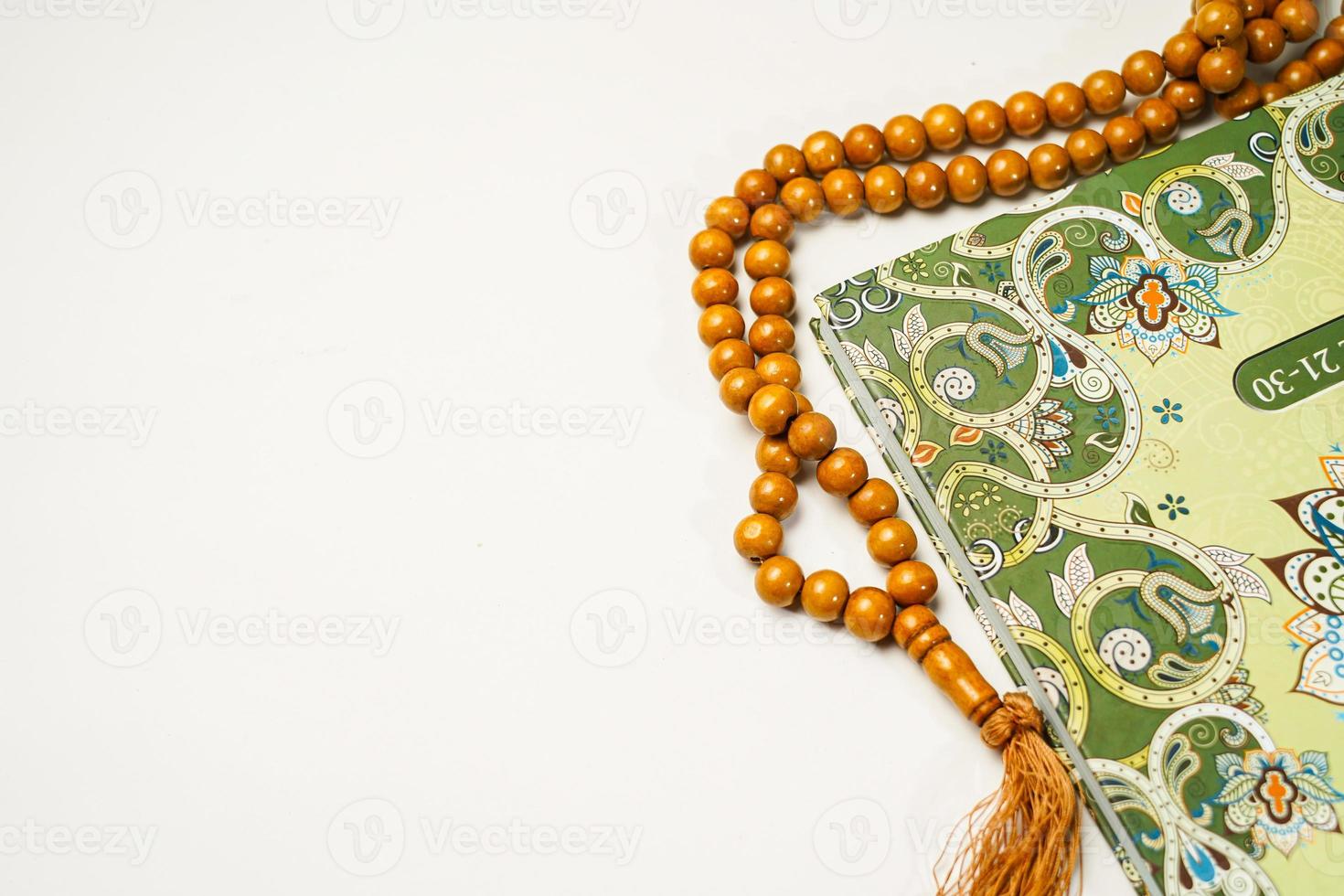 The Holy Al Quran with written arabic calligraphy meaning of Al Quran and rosary beads or tasbih on white background with copy space. photo