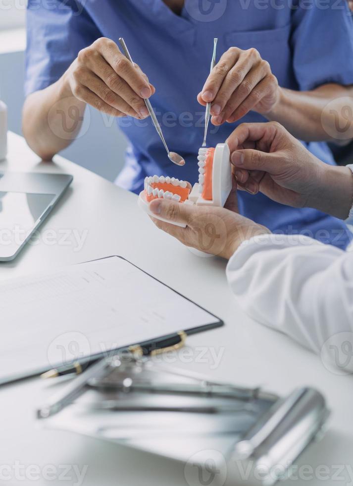 los dentistas están discutiendo problemas dentales al informar la imagen de rayos X en la pantalla del portátil a los pacientes. foto