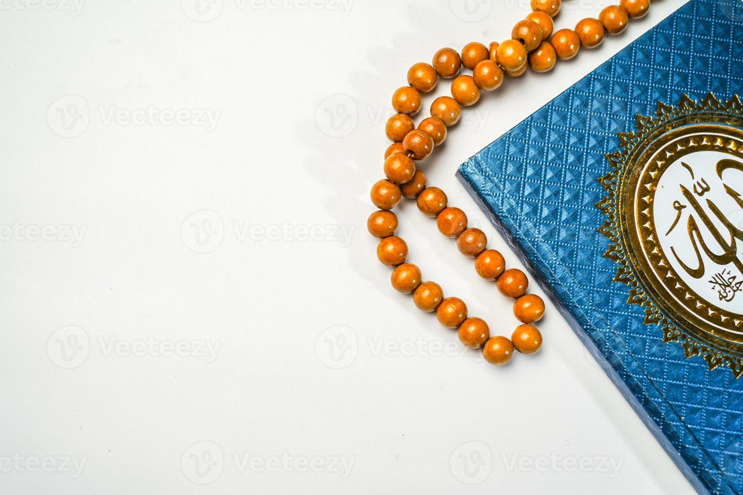 The Holy Al Quran with written arabic calligraphy meaning of Al Quran and rosary beads or tasbih on white background with copy space. photo