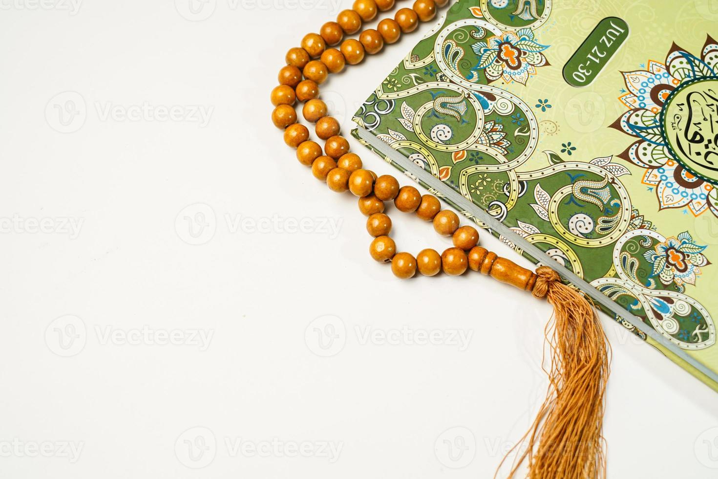 The Holy Al Quran with written arabic calligraphy meaning of Al Quran and rosary beads or tasbih on white background with copy space. photo