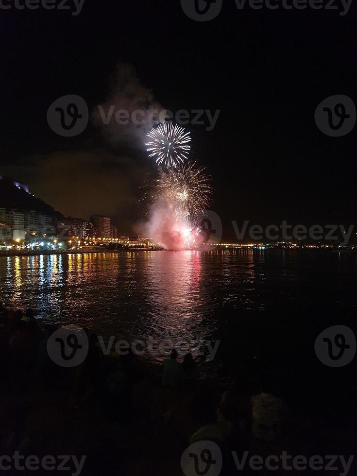 fuegos artificiales espectáculo a noche en el costas de el mar de alicante España foto