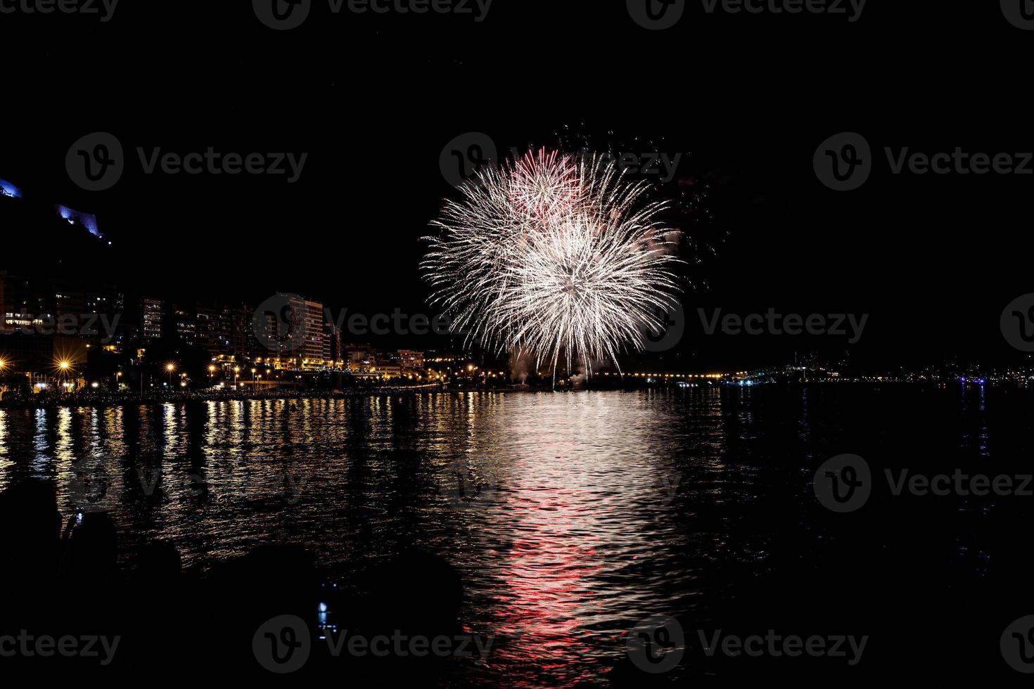 fuegos artificiales espectáculo a noche en el costas de el mar de alicante España foto