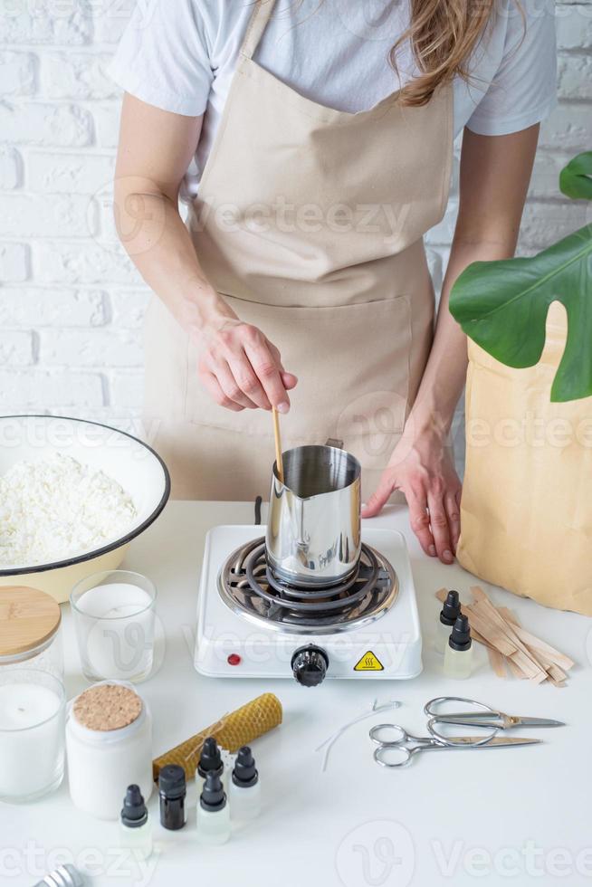 Woman making decorative aroma candles at table photo